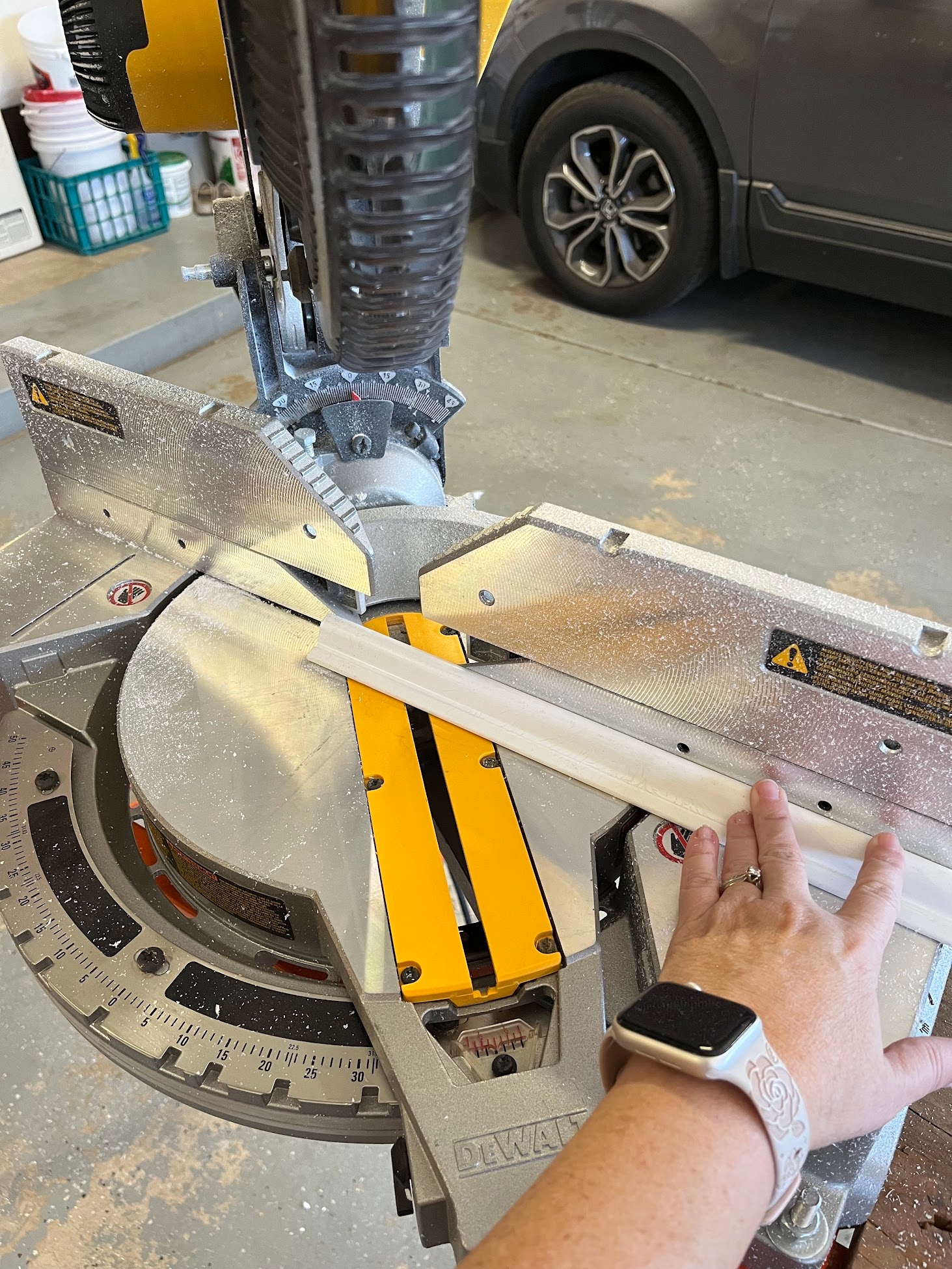 Using a mitre saw to cut white PVC molding pieces.