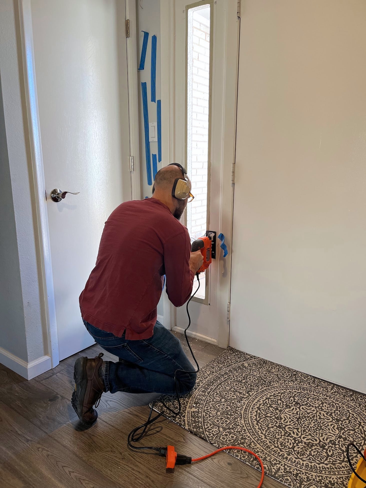 Using a jigsaw to cut a larger opening in the sidelight of the front door.