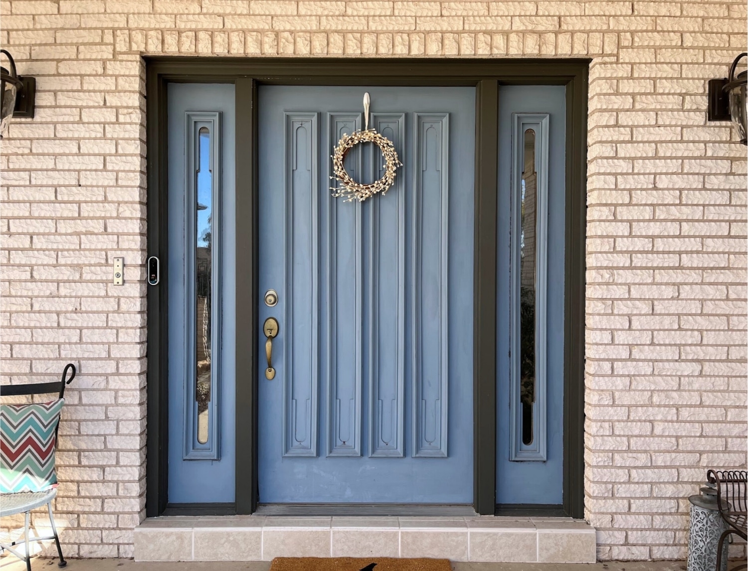 A dusty blue front door with molding and black trim.